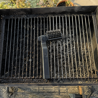 Parrilla con la mitad sucia y la mitad ya limpia, con el cepillo apoyado entre ambas